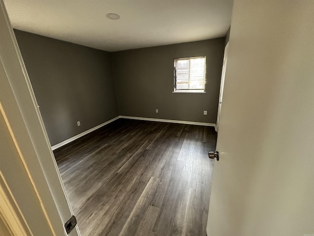 spare room with dark wood-style flooring and baseboards