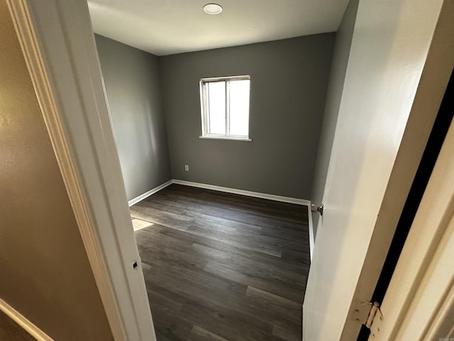 spare room featuring baseboards and dark wood-style flooring