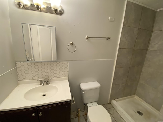 bathroom featuring a tile shower, vanity, and toilet