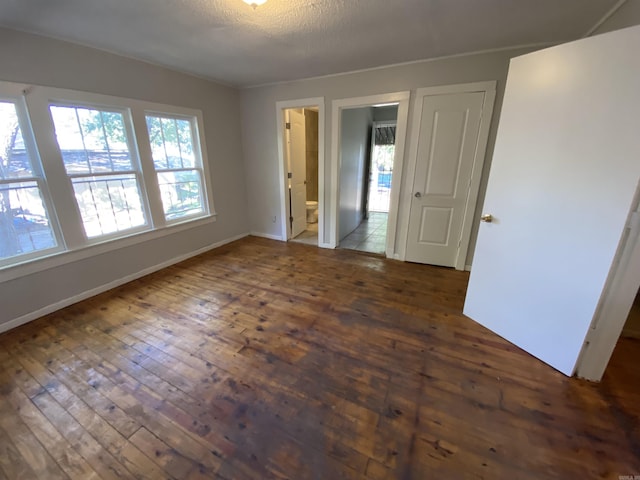 spare room with a textured ceiling, baseboards, and dark wood-type flooring