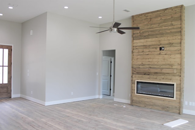 unfurnished living room with light wood-style floors, baseboards, a ceiling fan, and a glass covered fireplace