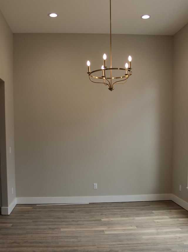 unfurnished room featuring an inviting chandelier, baseboards, wood finished floors, and recessed lighting