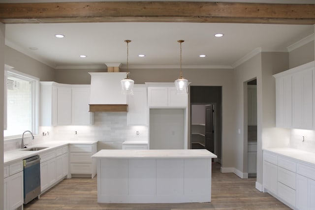 kitchen featuring white cabinetry, light countertops, stainless steel dishwasher, a center island, and decorative light fixtures