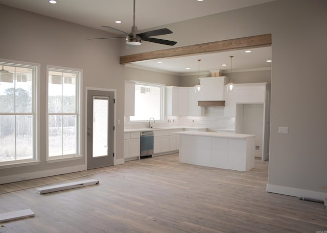 kitchen featuring a kitchen island, white cabinetry, light countertops, stainless steel dishwasher, and decorative light fixtures