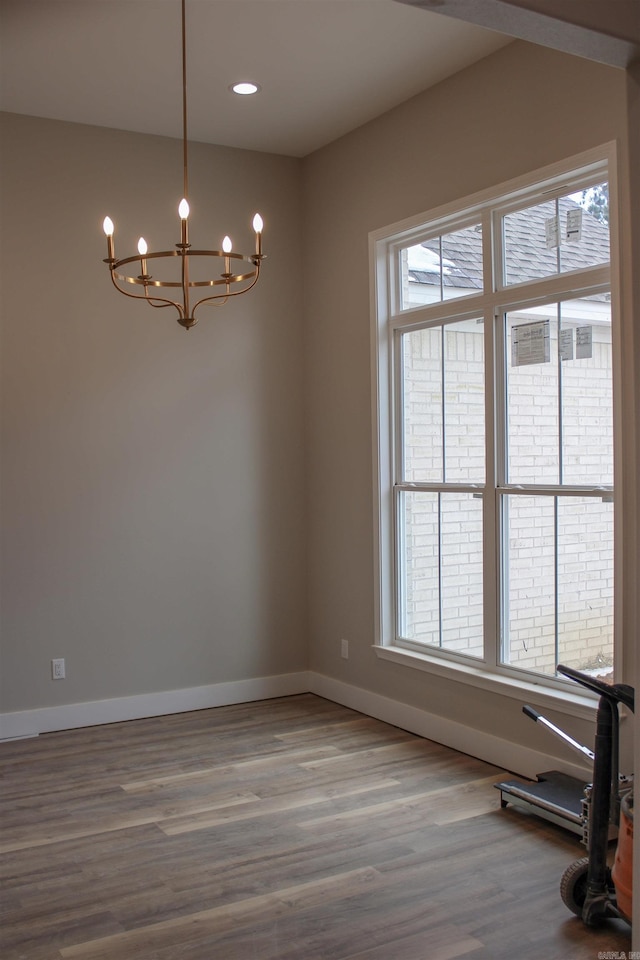 unfurnished room featuring baseboards, a chandelier, wood finished floors, and recessed lighting