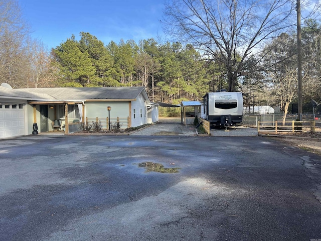 exterior space featuring aphalt driveway, an attached garage, and fence