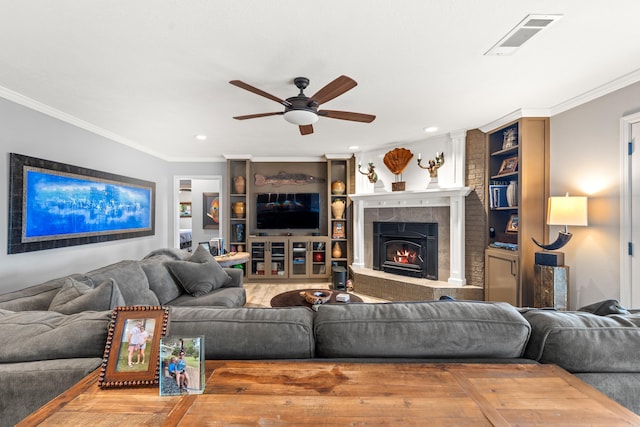 living room with a warm lit fireplace, ornamental molding, visible vents, and a ceiling fan