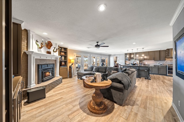 living room with a textured ceiling, french doors, light wood finished floors, and crown molding