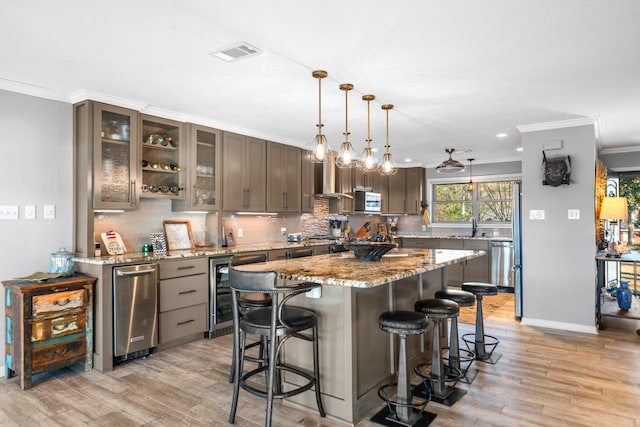 kitchen featuring light stone counters, a kitchen island, glass insert cabinets, and pendant lighting