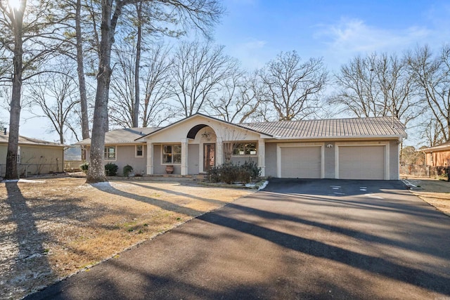 ranch-style home with a garage, metal roof, driveway, and a standing seam roof