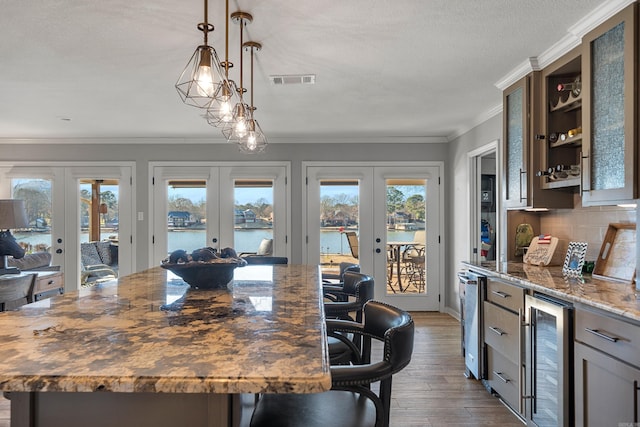 kitchen featuring dark stone countertops, french doors, wine cooler, and a water view