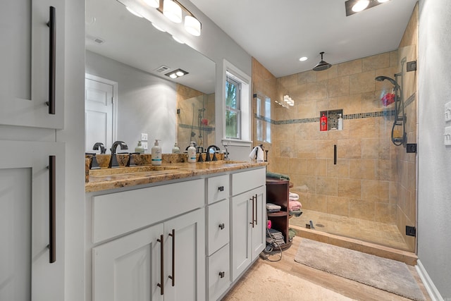 full bath with double vanity, a stall shower, visible vents, and a sink