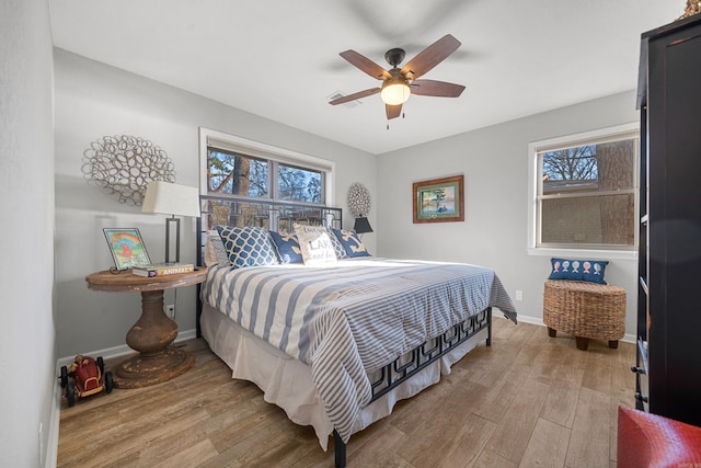 bedroom featuring multiple windows, baseboards, and wood finished floors