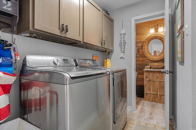 laundry area with light wood-type flooring, cabinet space, and washer and clothes dryer