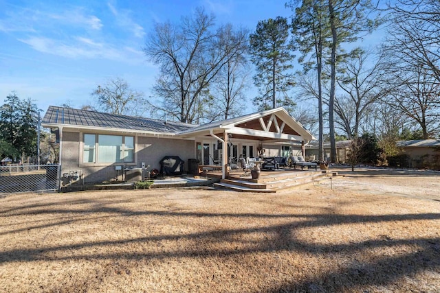 back of property with brick siding, a yard, a patio, metal roof, and fence