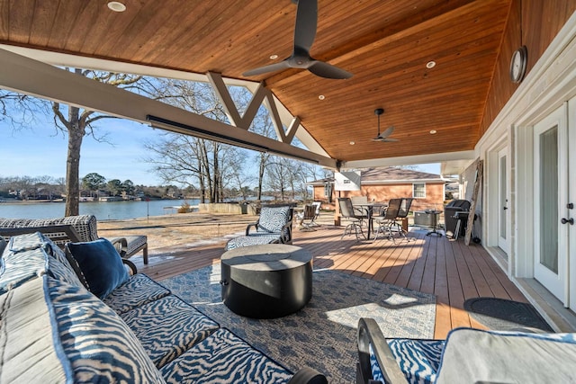 wooden terrace with outdoor lounge area, a water view, a grill, a ceiling fan, and outdoor dining space