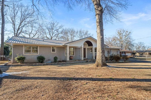 view of front of home with a garage, a front yard, metal roof, and brick siding