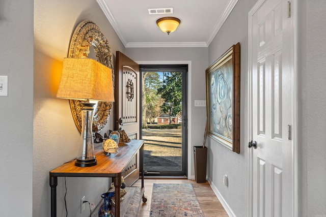 doorway with visible vents, crown molding, light wood-style flooring, and baseboards