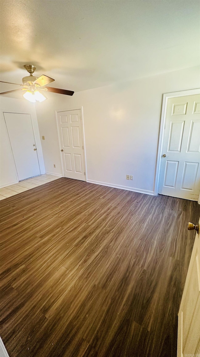 unfurnished bedroom featuring baseboards, a ceiling fan, and dark wood-type flooring