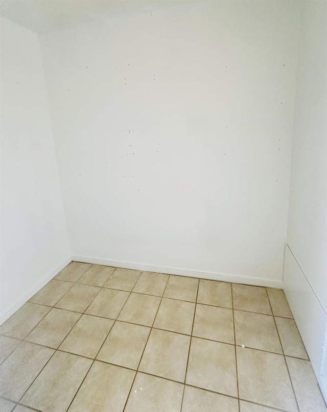 empty room featuring baseboards and light tile patterned floors