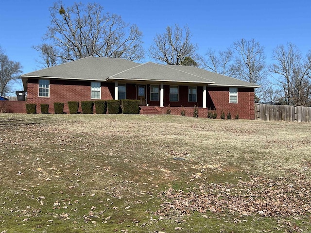 single story home featuring brick siding, fence, and a front lawn