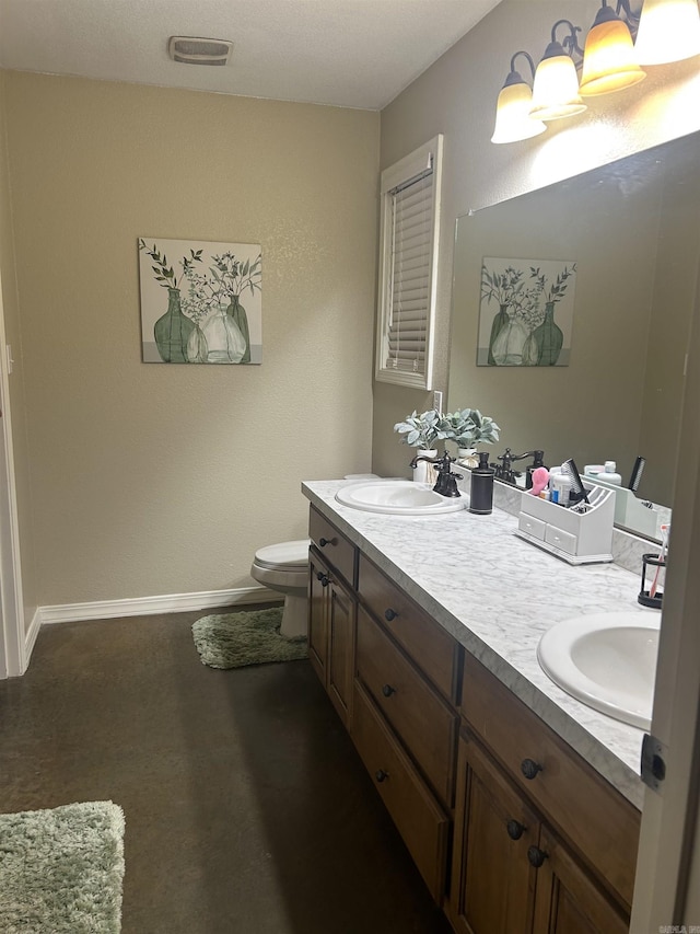 full bathroom with toilet, double vanity, baseboards, and a sink