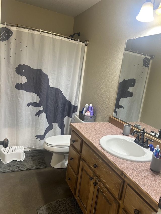 bathroom with a textured wall, vanity, and toilet