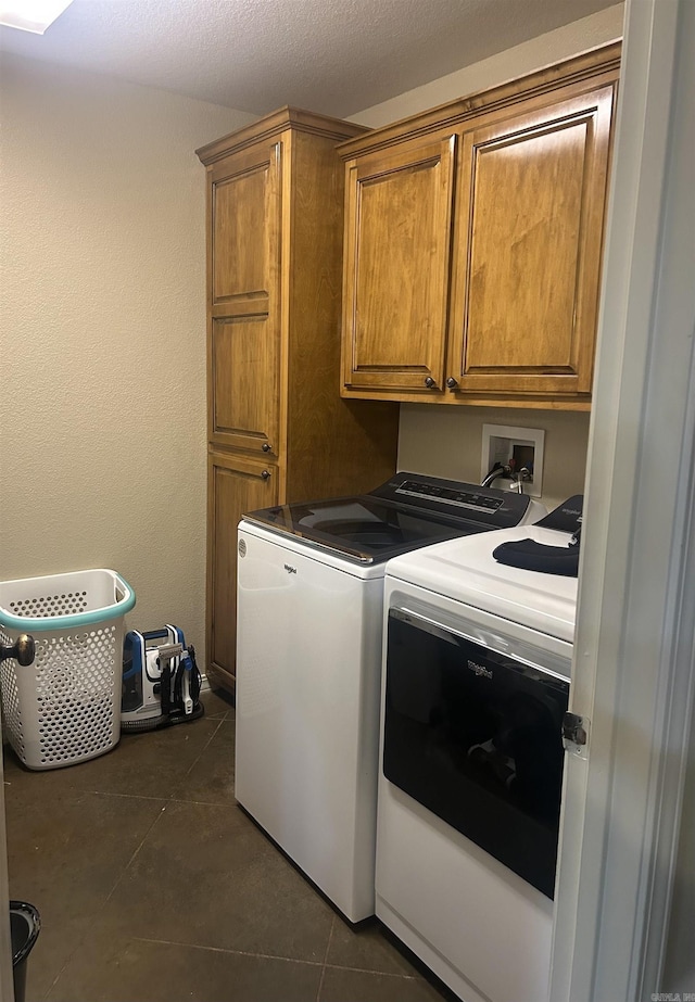 clothes washing area featuring dark tile patterned flooring, separate washer and dryer, and cabinet space