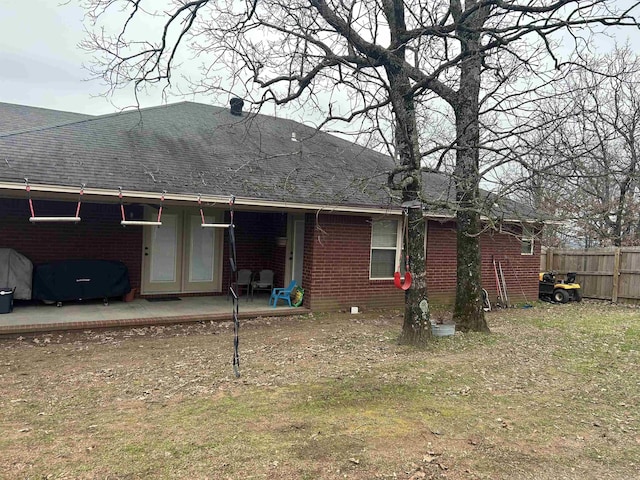 back of house with a shingled roof, fence, a yard, a patio area, and brick siding