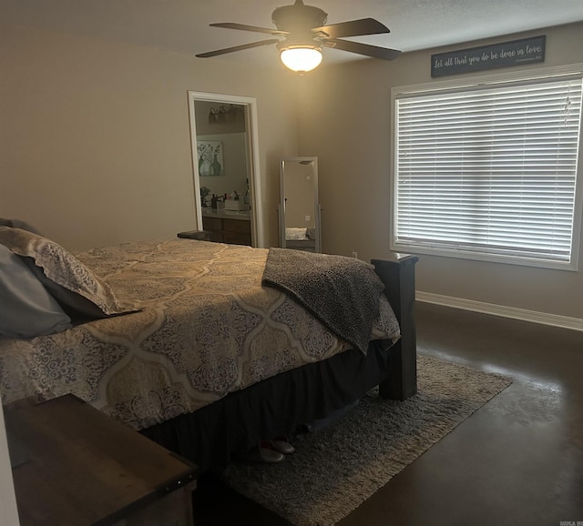 bedroom with finished concrete floors, connected bathroom, baseboards, and a ceiling fan