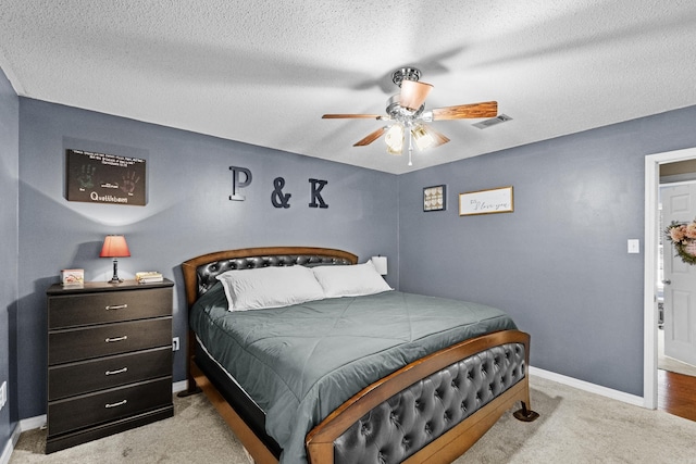 bedroom with light colored carpet, visible vents, a ceiling fan, a textured ceiling, and baseboards