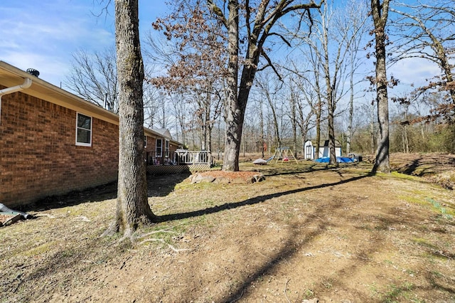 view of yard featuring an outbuilding, a shed, and a deck