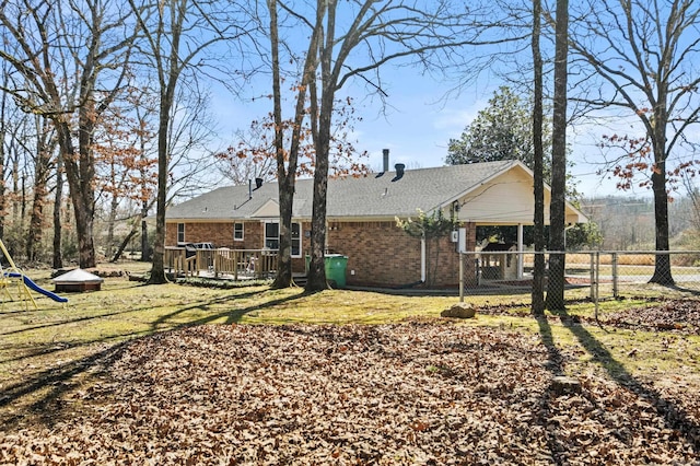 view of home's exterior featuring fence, a deck, a lawn, and brick siding