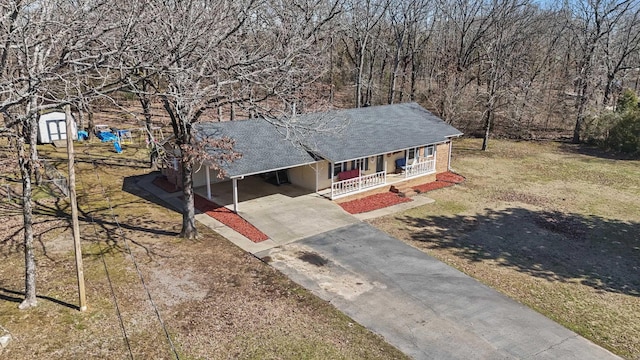 view of front facade with a shingled roof, covered porch, a front yard, an attached carport, and driveway