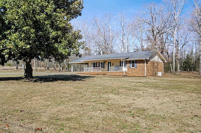 view of front of property featuring a porch, brick siding, a carport, and a front lawn