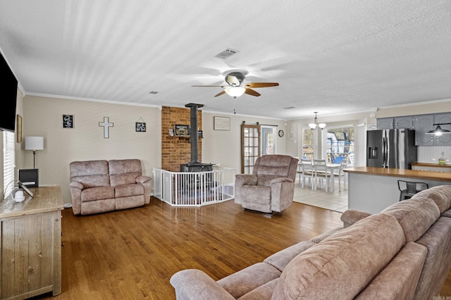 living room with a textured ceiling, wood finished floors, visible vents, and crown molding