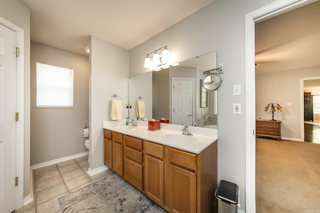 full bathroom with double vanity, toilet, a sink, and tile patterned floors