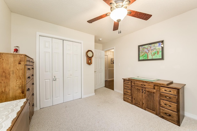 bedroom with a closet, light colored carpet, ceiling fan, a textured ceiling, and baseboards