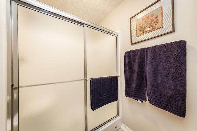 full bathroom with a shower with door and a textured ceiling