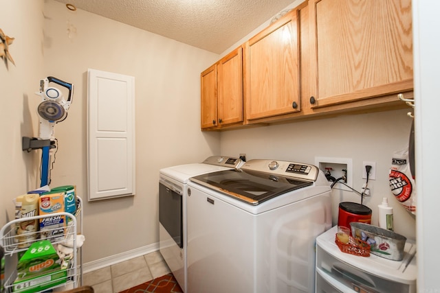 washroom with cabinet space, light tile patterned flooring, a textured ceiling, independent washer and dryer, and baseboards