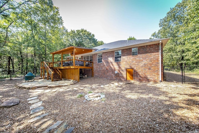 back of property with stairway, fence, a deck, a patio area, and brick siding