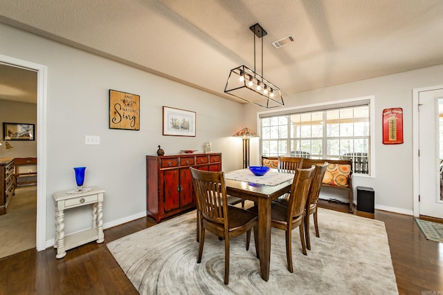 dining room featuring dark wood-style flooring, visible vents, a textured ceiling, and baseboards