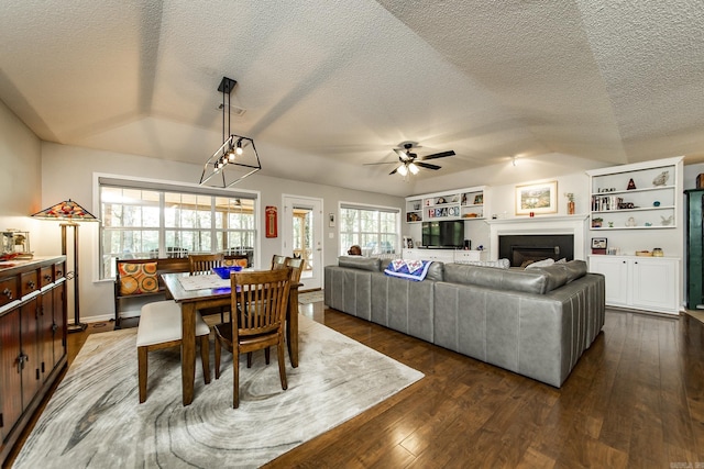 dining room with dark wood-style floors, ceiling fan, a textured ceiling, and a fireplace