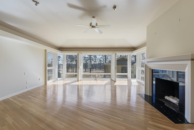 unfurnished living room featuring light wood-style flooring, baseboards, a raised ceiling, and a wealth of natural light