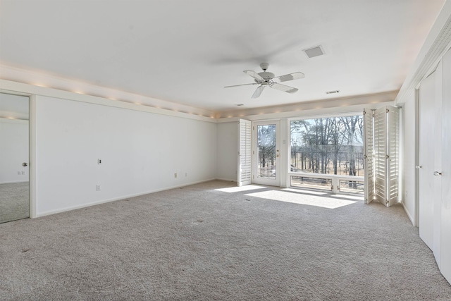 empty room with light colored carpet, ceiling fan, visible vents, and baseboards