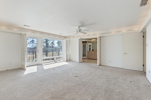 interior space featuring baseboards, visible vents, a ceiling fan, and light colored carpet