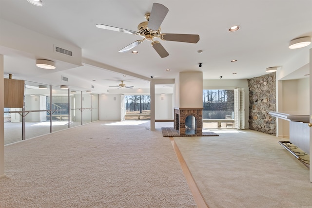 unfurnished living room with light carpet, a healthy amount of sunlight, a fireplace, and visible vents