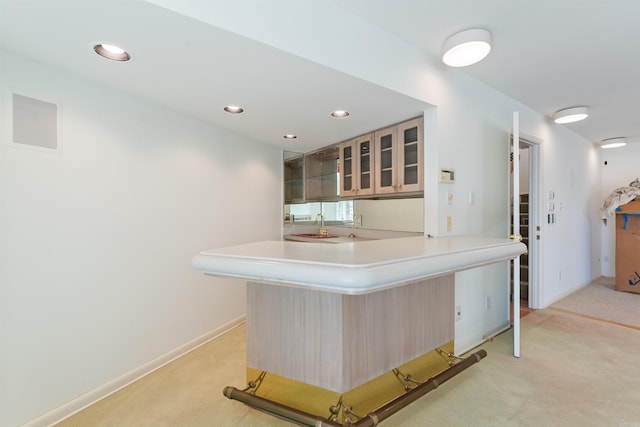 kitchen with recessed lighting, light colored carpet, light countertops, glass insert cabinets, and a peninsula