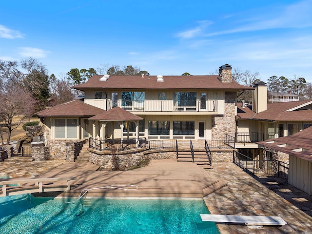 outdoor pool with a diving board and a patio area