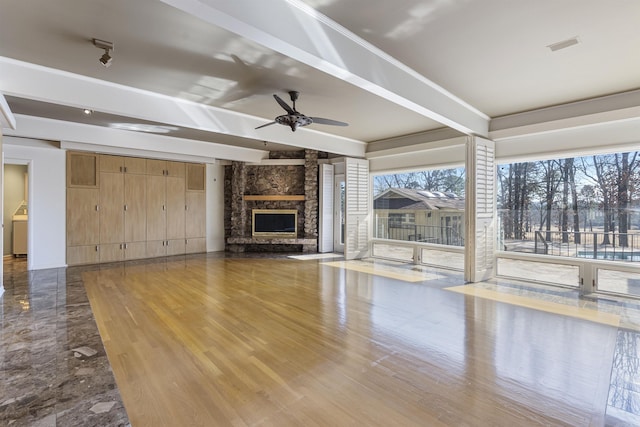 unfurnished living room featuring ceiling fan, washer / clothes dryer, beamed ceiling, and wood finished floors